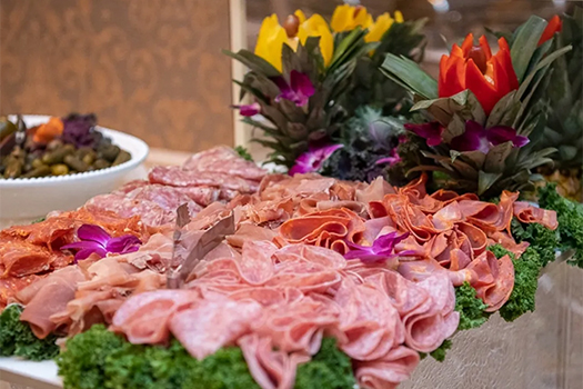 Platter of different meats with tropical flower arrangement